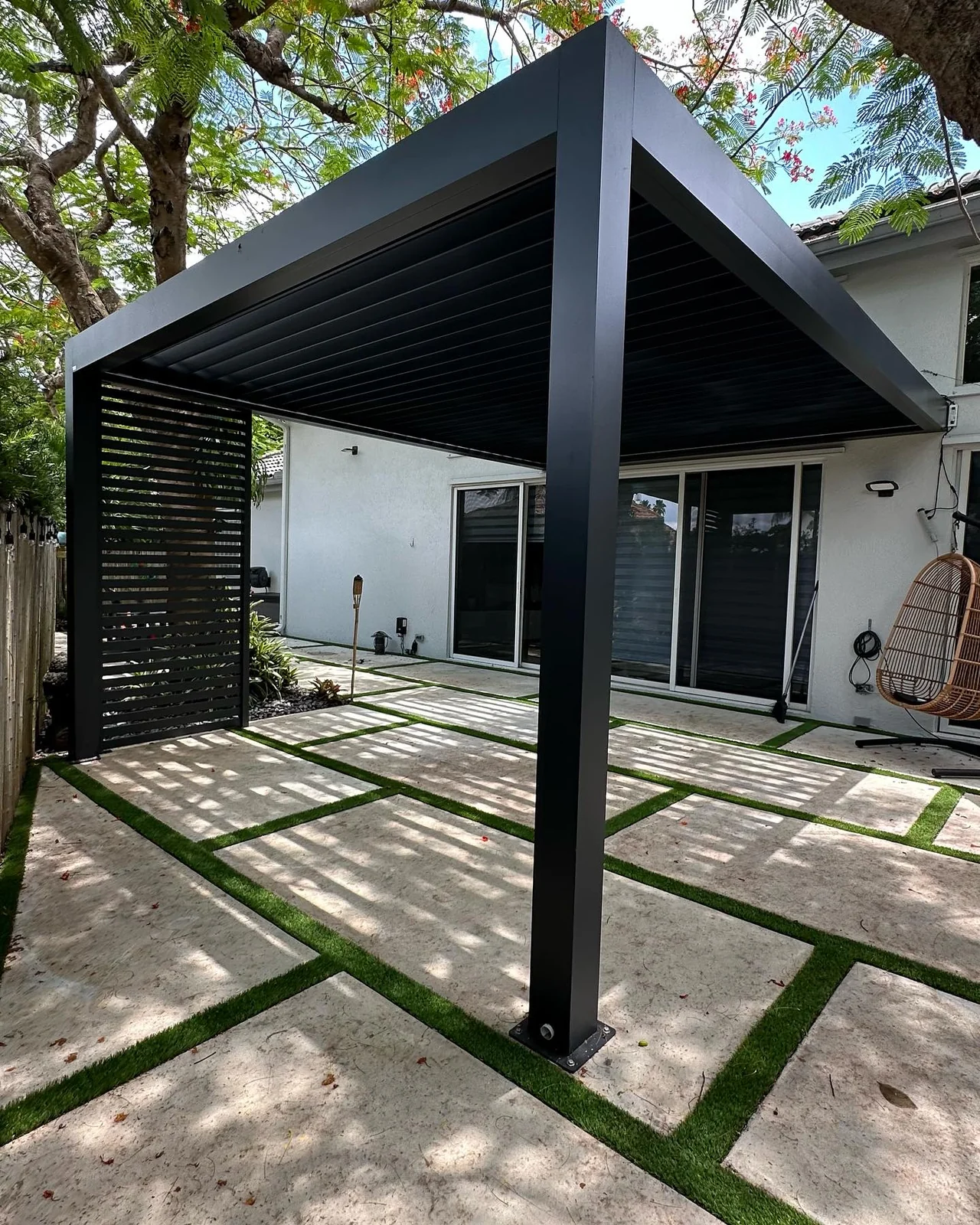 Charcoal wall-mounted louvered pergola with a slatted side panel in a Miramar backyard