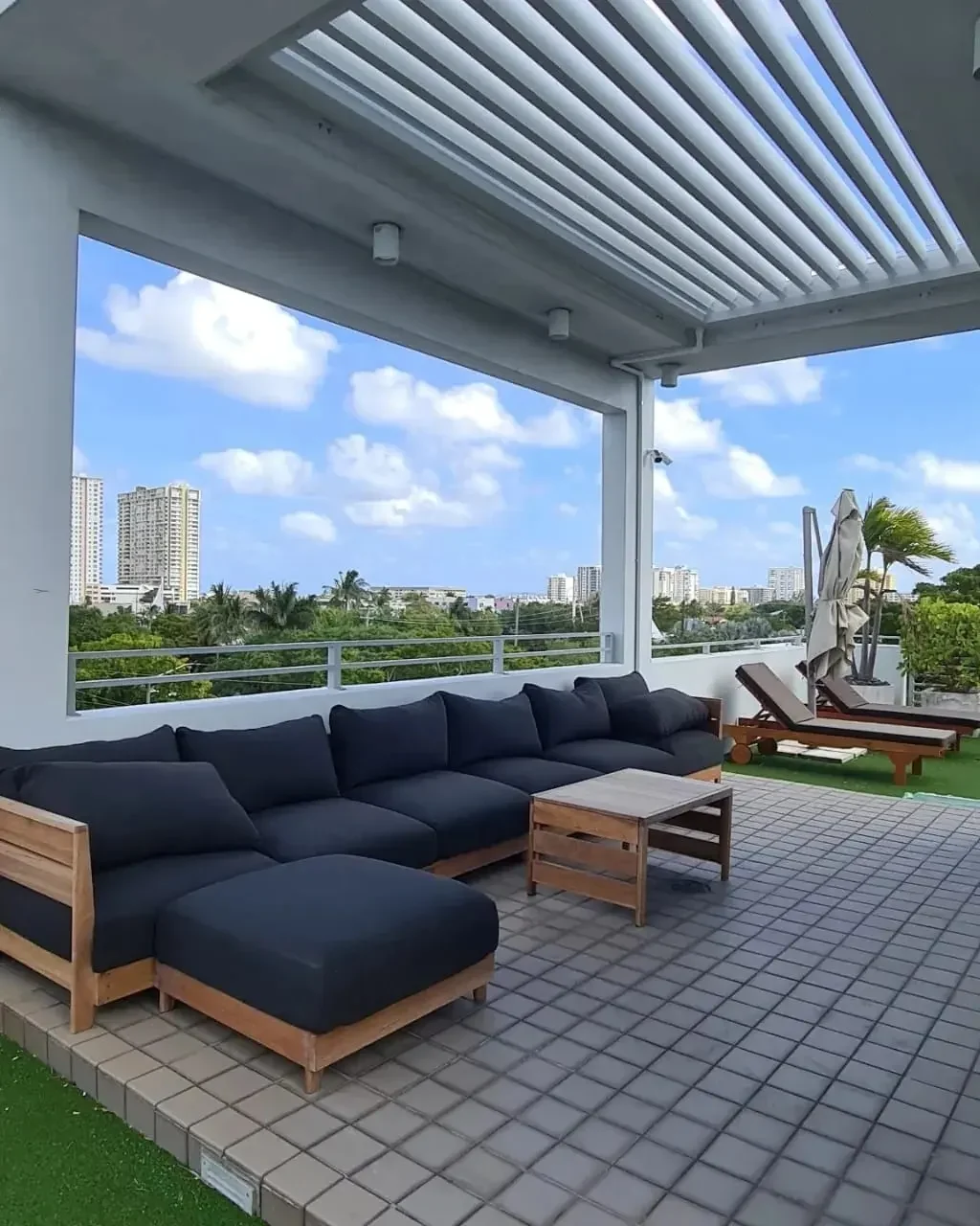 Dark sectional seating beneath white open louvers on the Pompano Beach terrace